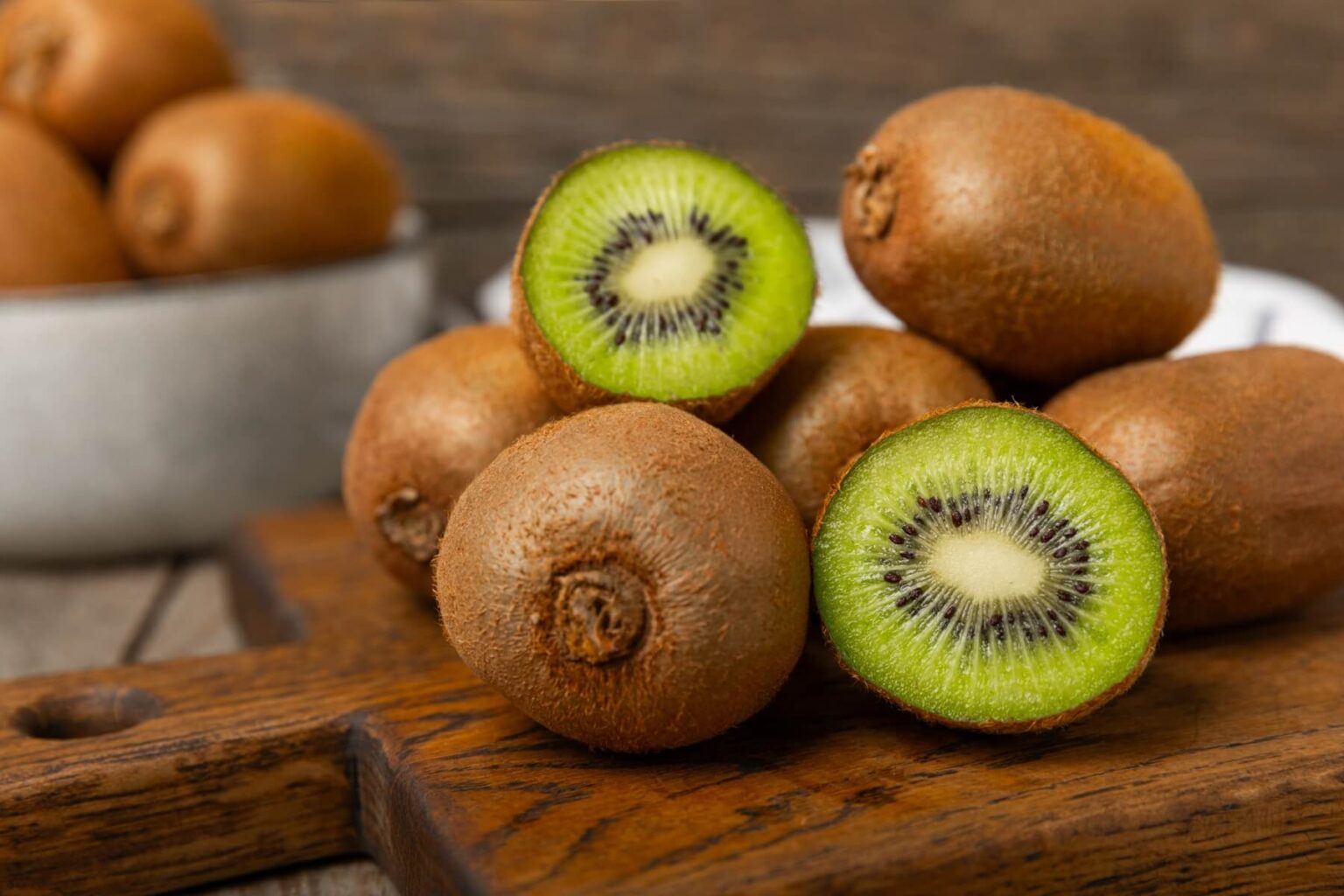 Kiwi na drewnianym tle. Całe owoce i kawałki zielonego kiwi na stole. świeże dojrzałe soczyste kiwi. Owoce tropikalne. Owoce ekologiczne. Zdrowe odżywianie. Spacja dla tekstu. Kopiuj spację.